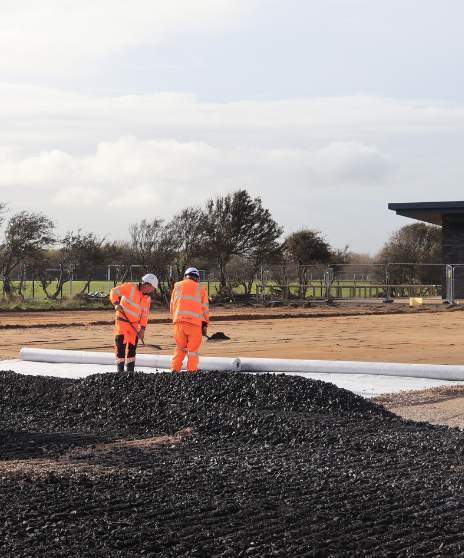 two people shovelling gravel base layer
