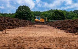 Sports Pitch Construction with digger driving past