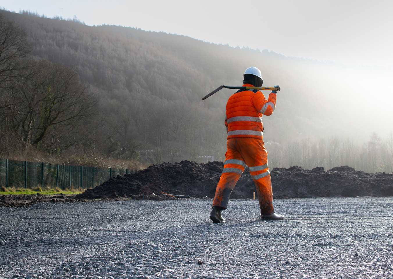 man on site with shovel over shoulder